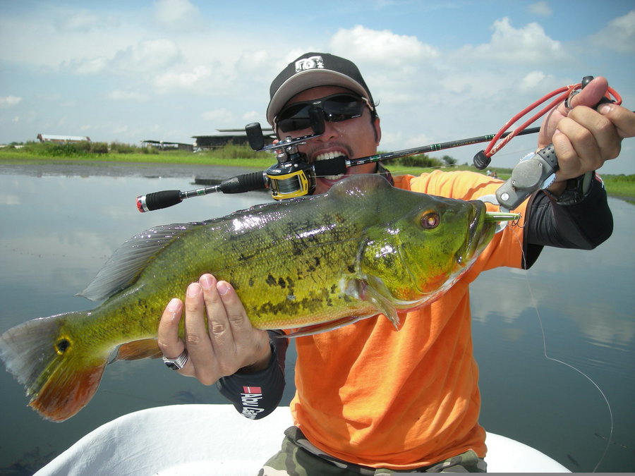 Angler proudly holds a large fish while fishing from a boat.