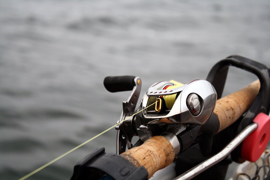 Baitcasting reel mounted on a fishing rod with yellow line.