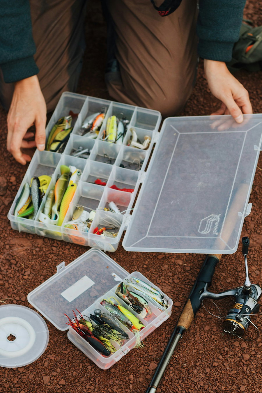 Tackle boxes filled with various fishing lures and a fishing rod nearby.