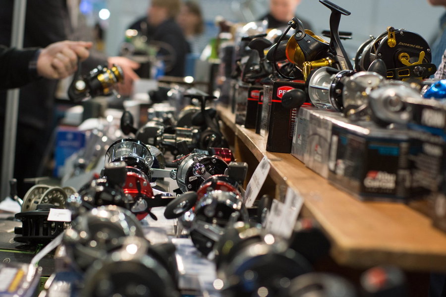 Various fishing reels displayed on a wooden table at an exhibition.