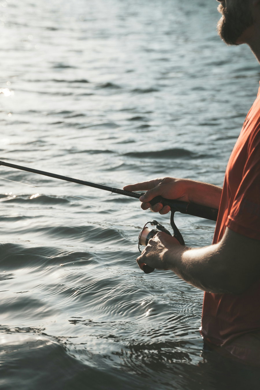 Person fishing with a spinning reel in calm water.