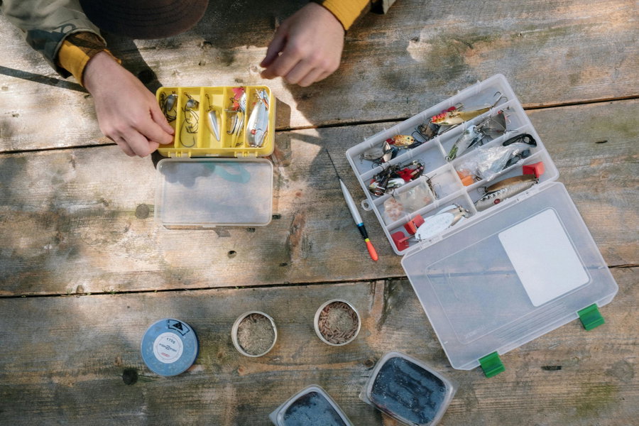 Fishing tackle boxes filled with lures and bait on a wooden table.