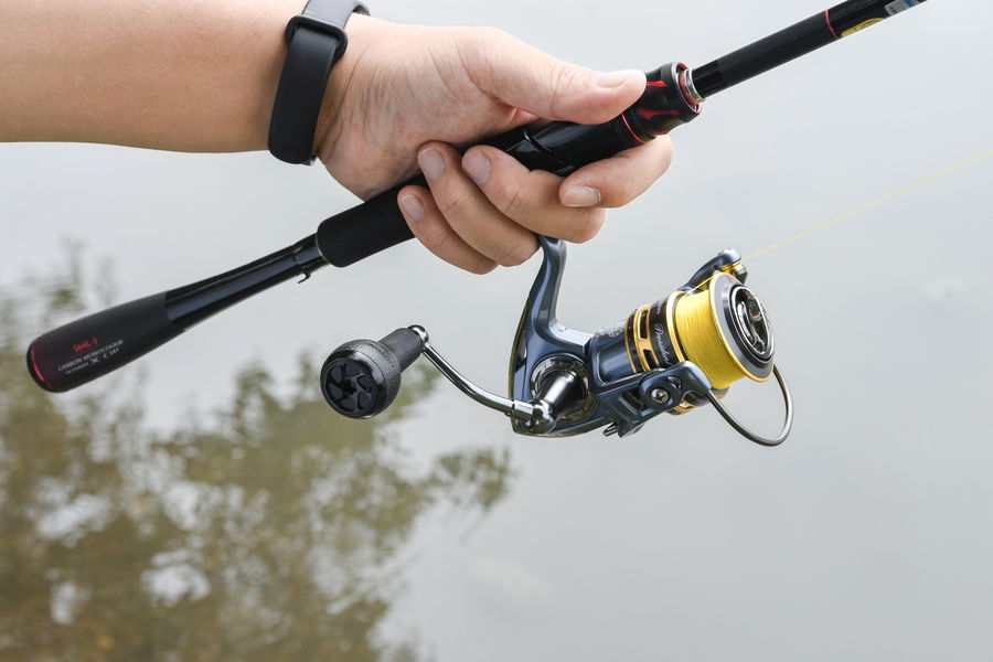 Spinning fishing reel mounted under the rod, showing open spool and line guide.