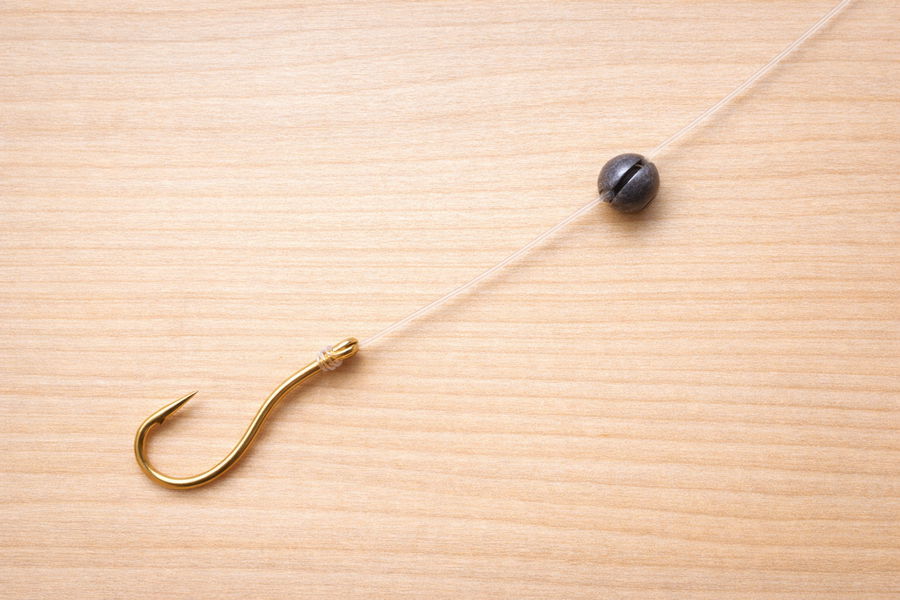 Simple beginner fishing setup with hook, weight, and swivel arranged clearly on a wooden surface.