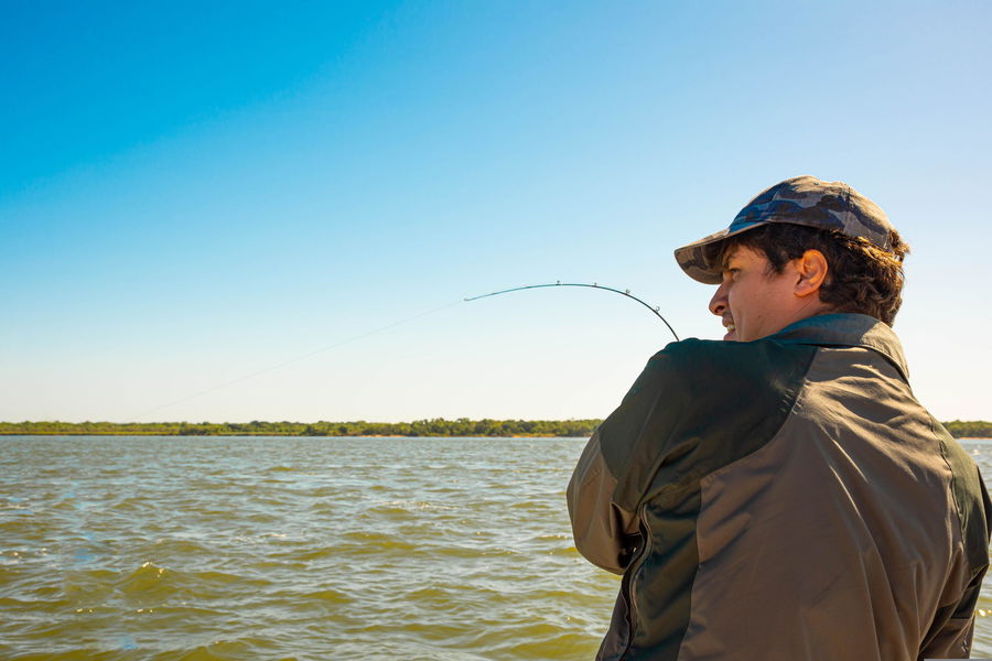 Angler setting the hook with a spinning rod, showing proper upward motion and rod bend under tension.